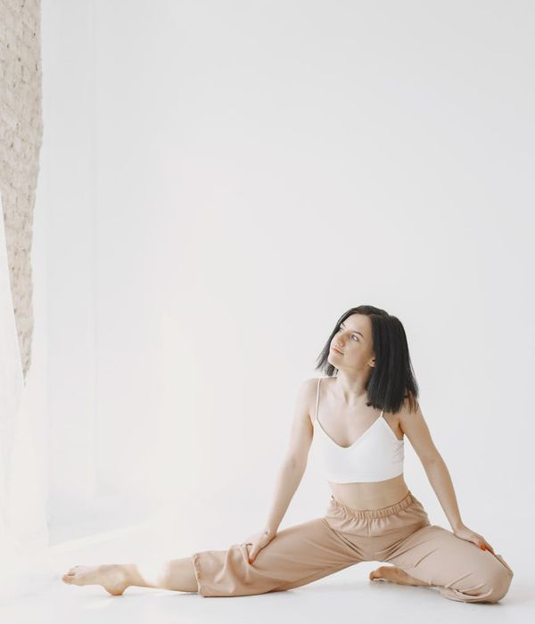 Woman in a calming yoga pose, bathed in soft emerald light.